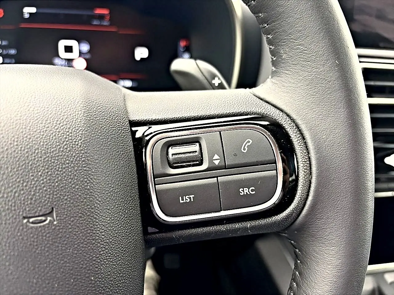 Gros plan sur les commandes multifonctions à gauche du volant cuir du Citroën C5 Aircross 2025, finition noire.