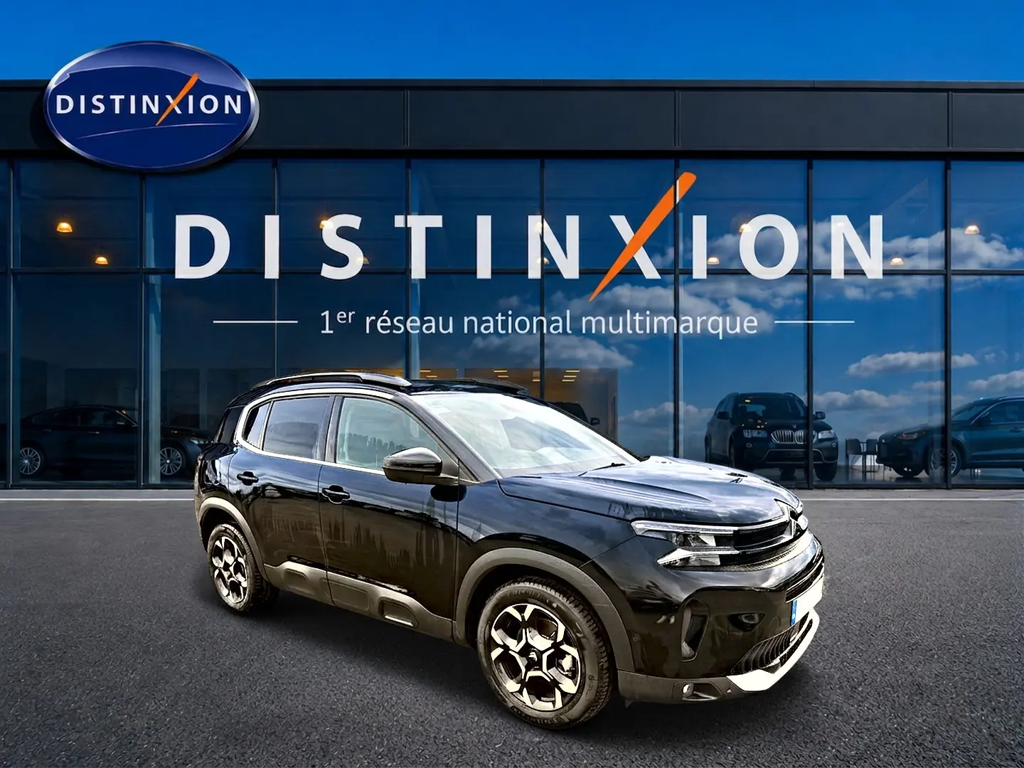 Citroën C5 Aircross noir vue 3/4 avant droit avec jantes alu et barres de toit devant vitrine Distinxion.