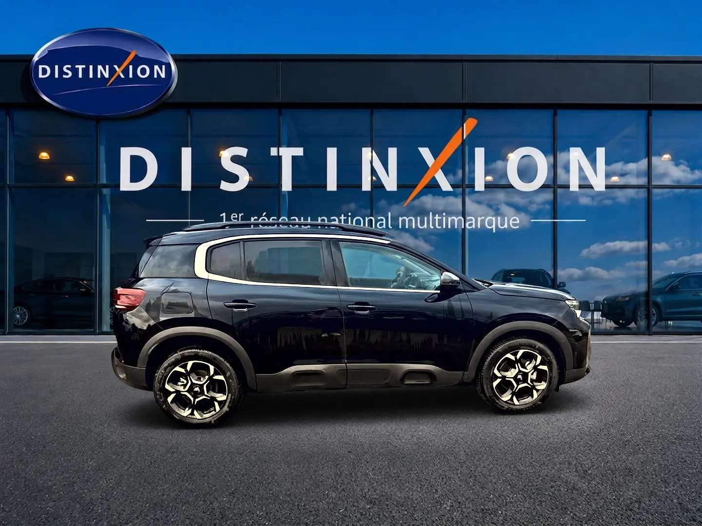 Profil droit du Citroën C5 Aircross noir 2025 avec jantes alu et barres de toit devant vitrine Distinxion.
