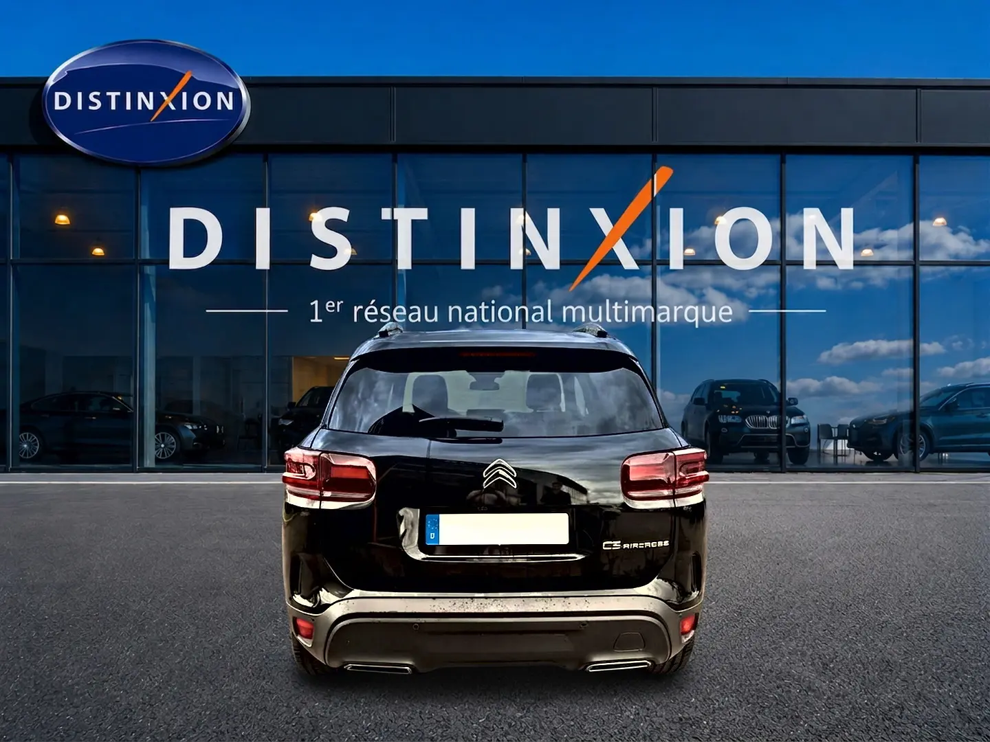 Vue arrière d'un Citroën C5 Aircross noir 2025 garé devant une vitrine avec logo Distinxion.