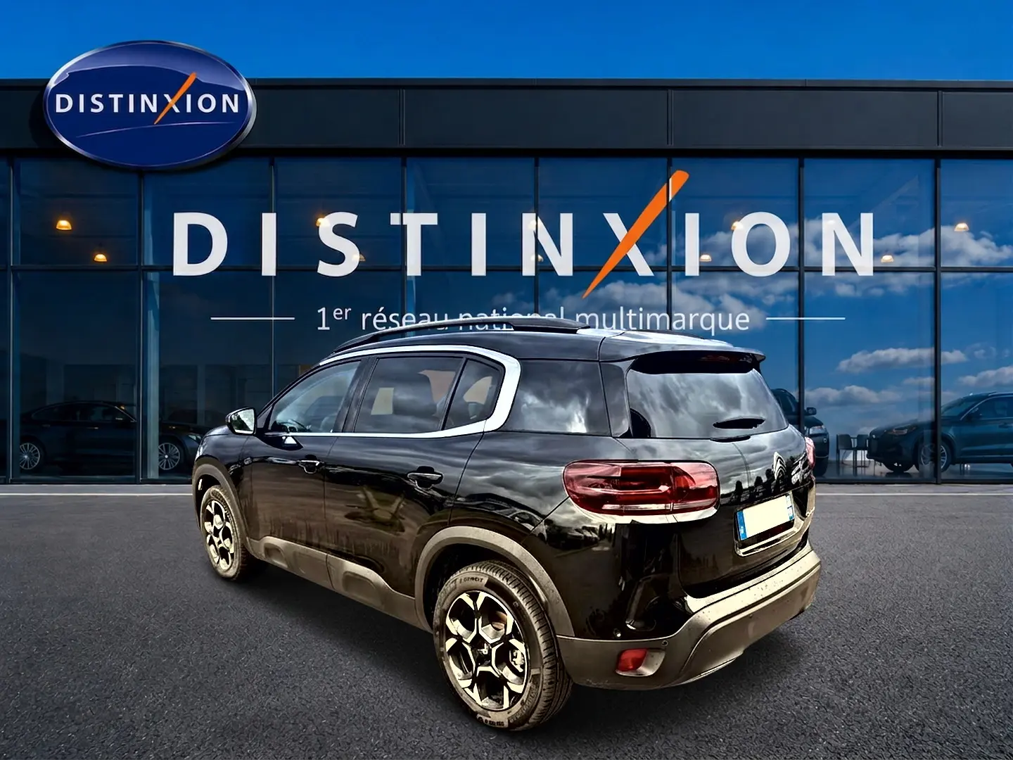 Vue 3/4 arrière droite d'un Citroën C5 Aircross noir avec jantes alu devant une vitrine Distinxion.