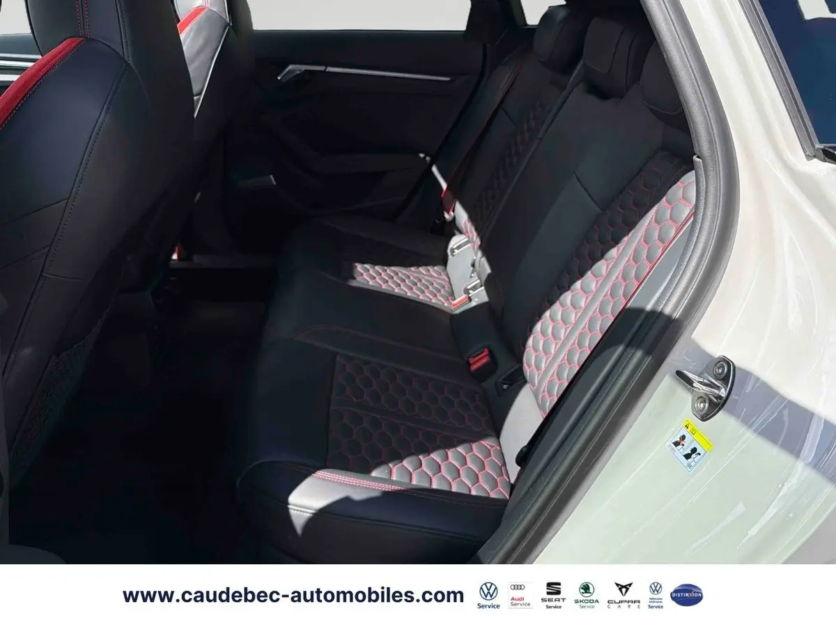 Vue côté droit de l'intérieur arrière de l'Audi RS3 Sportback avec sièges cuir noir à surpiqûres rouges en nid d'abeille.