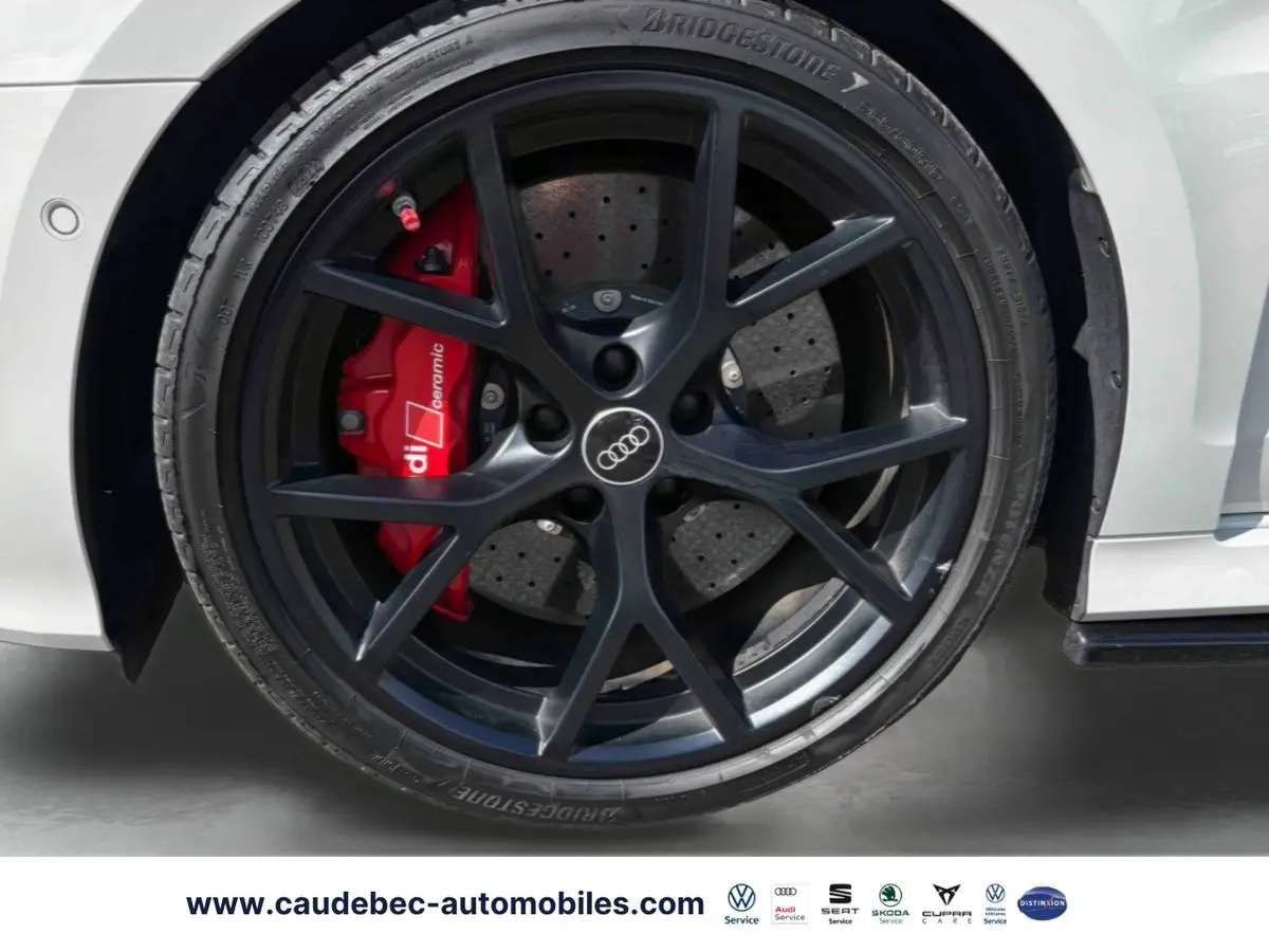 Gros plan sur la roue avant droite grise d’une Audi RS3 Sportback avec étrier de frein céramique rouge et jante noire mat à 5 branches en Y.