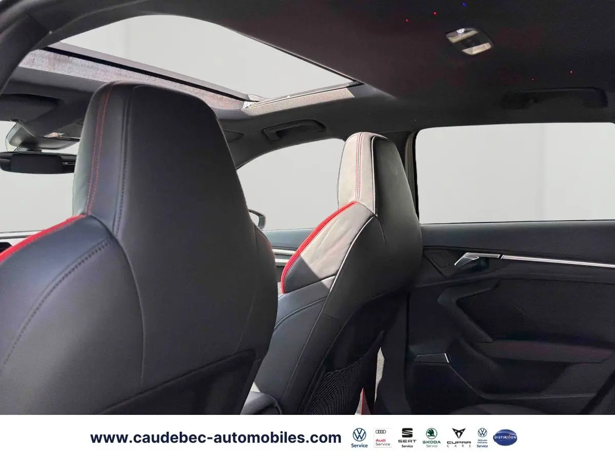 Vue intérieure arrière de l’Audi RS3 Sportback 2022, sièges cuir noir avec surpiqûres rouges et toit panoramique ouvrant.