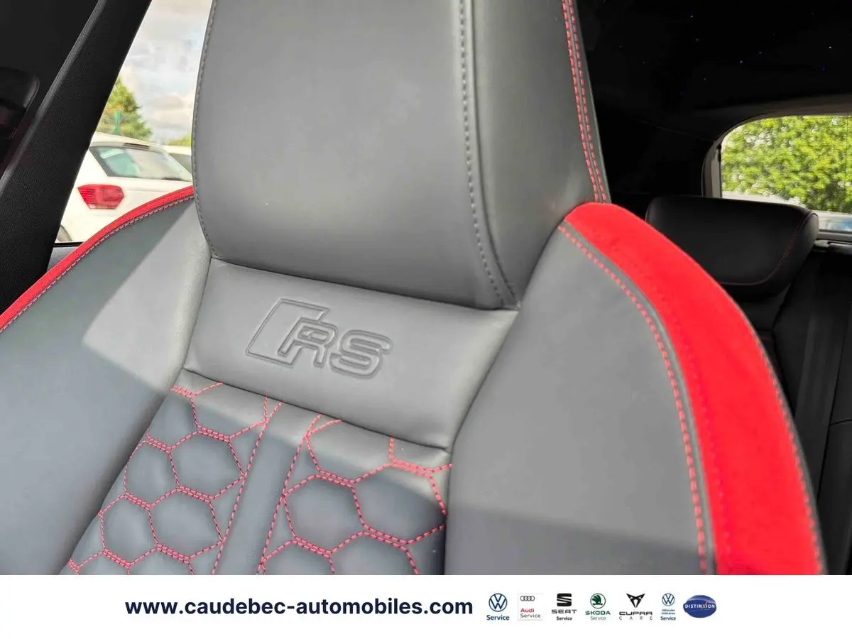 Gros plan sur le siège avant en cuir gris et alcantara rouge avec surpiqûres rouges et logo RS embossé.