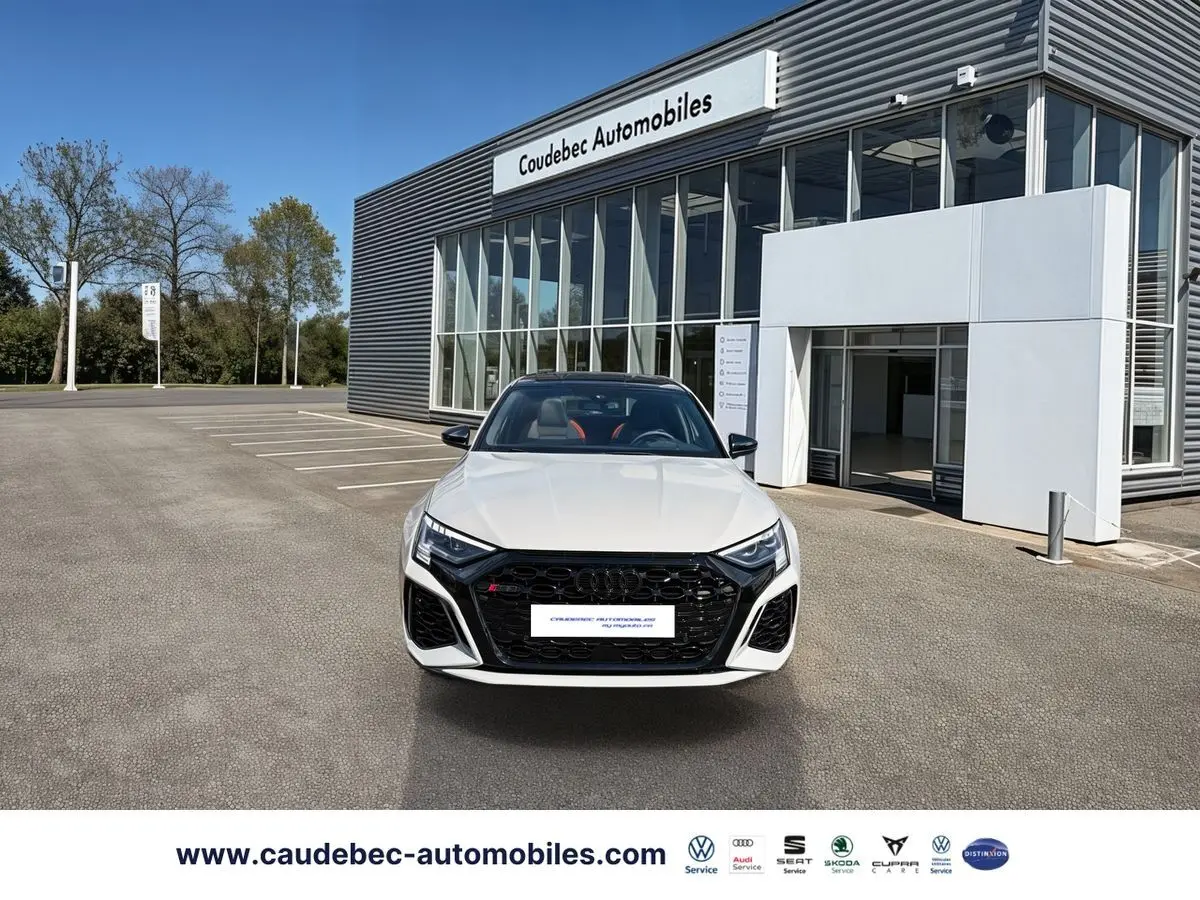 Audi RS3 Sportback vue de face en gris avec calandre noire et phares Matrix LED devant un showroom.