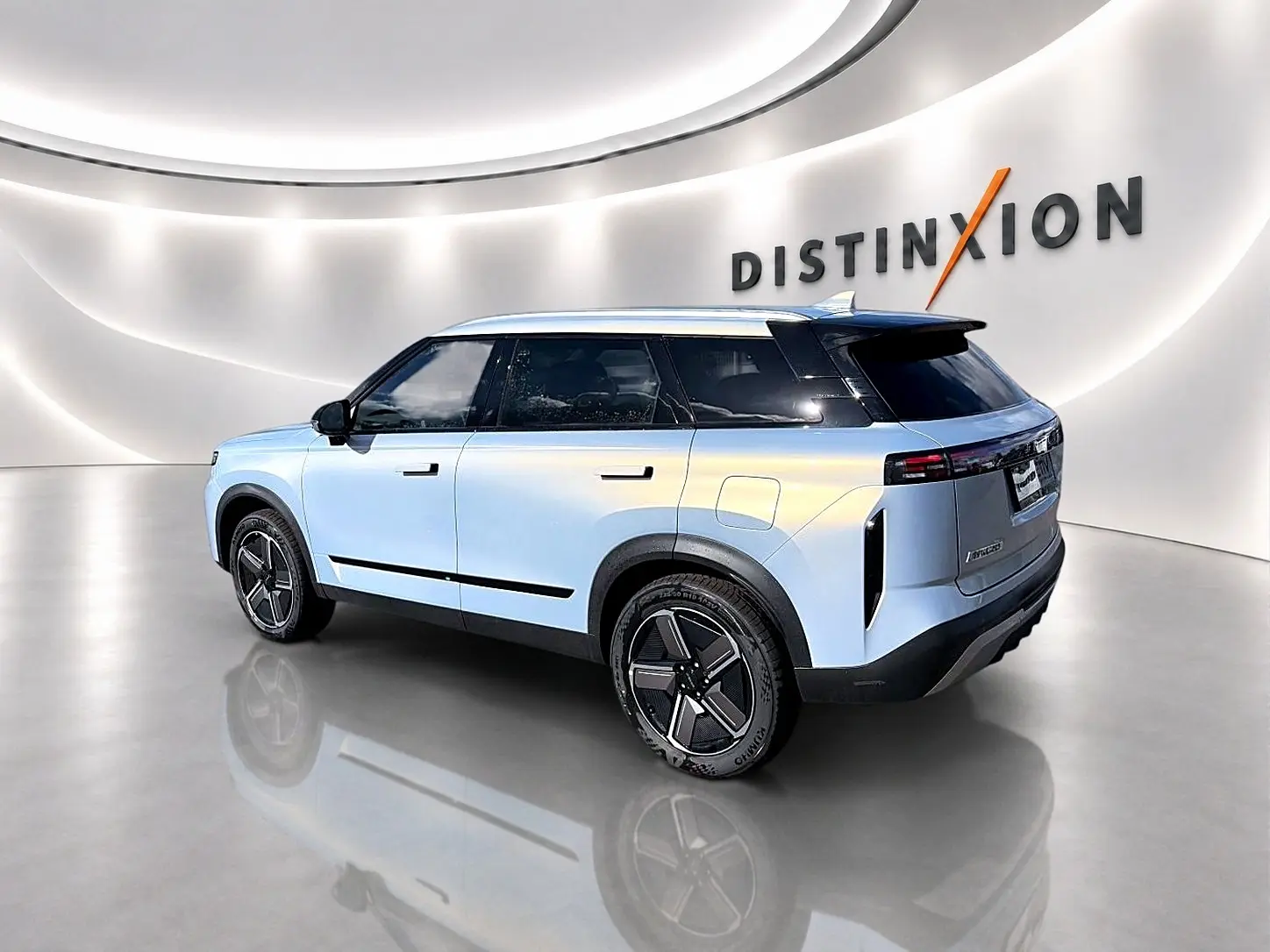 Vue 3/4 arrière droite du JAECOO J7 gris moonlight, avec toit noir et jantes alu modernes dans un showroom lumineux.