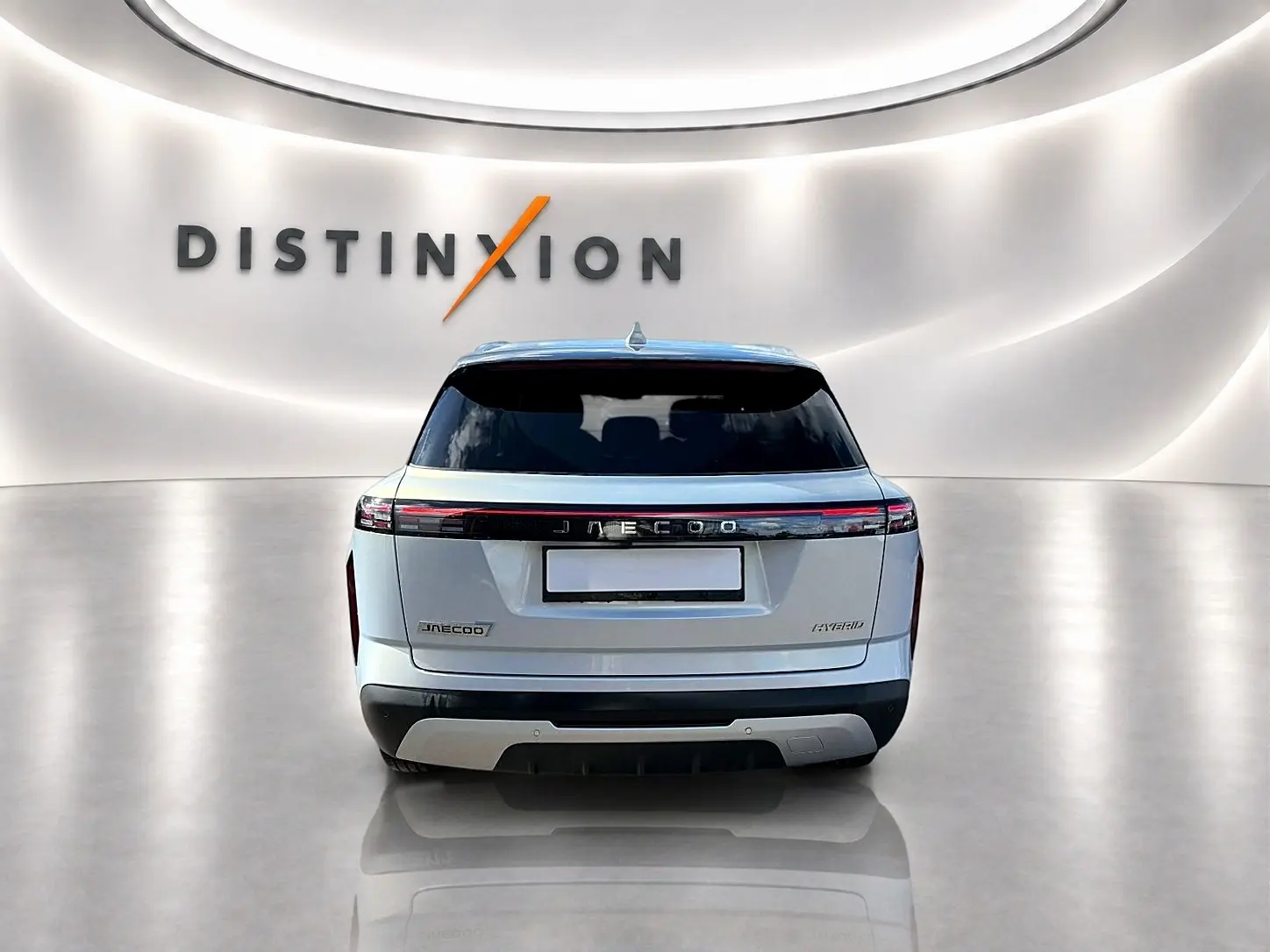 Vue arrière du SUV JAECOO J7 gris moonlight avec feux arrière à LED et toit panoramique en verre dans un showroom lumineux.
