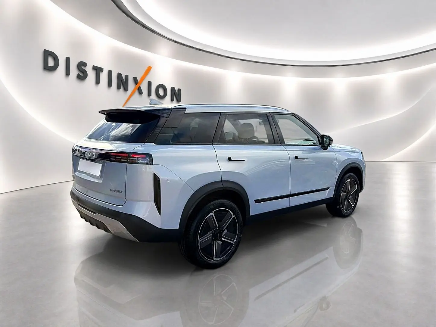 Vue 3/4 arrière droite du JAECOO J7 gris moonlight avec toit noir et jantes alu stylisées dans un showroom lumineux.