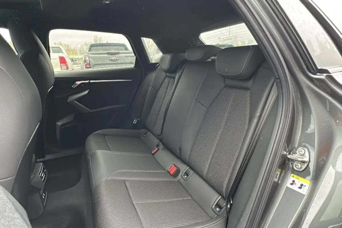 Vue intérieure arrière montrant les sièges en cuir tissu gris d'une Audi A3 2025 finition S-Line avec porte ouverte côté droit.