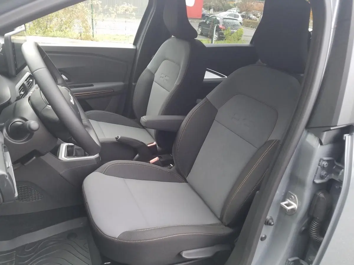Vue intérieure côté conducteur du Dacia Jogger gris urbain 2025, sièges avant chauffants avec surpiqûres contrastées.