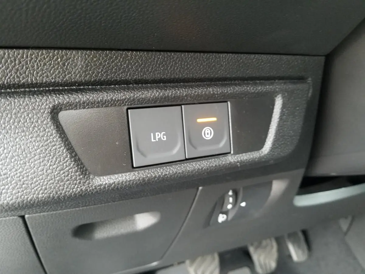 Gros plan sur les commandes LPG et verrouillage situées sous le tableau de bord du Dacia Jogger 2025.