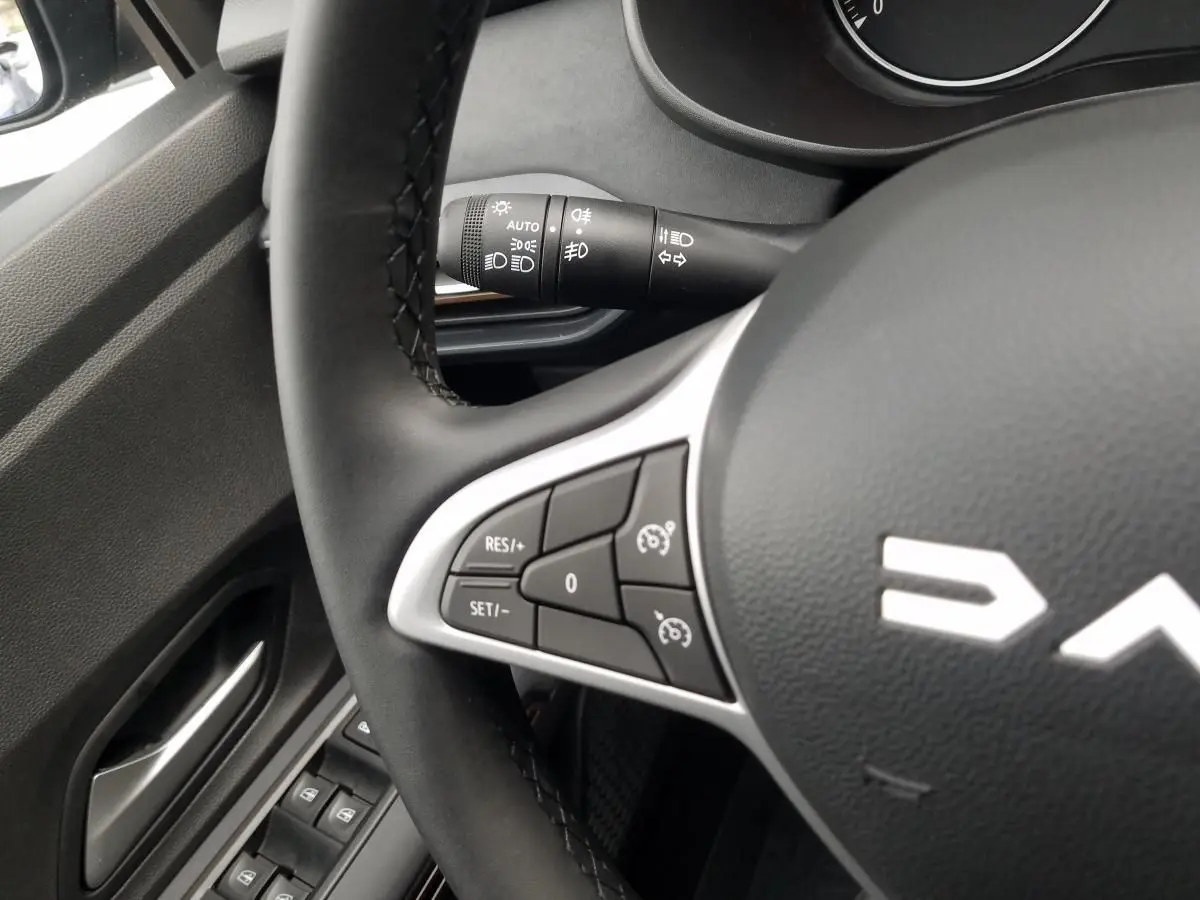 Gros plan sur le volant côté gauche du Dacia Jogger gris urbain 2025 avec commandes de régulateur de vitesse.