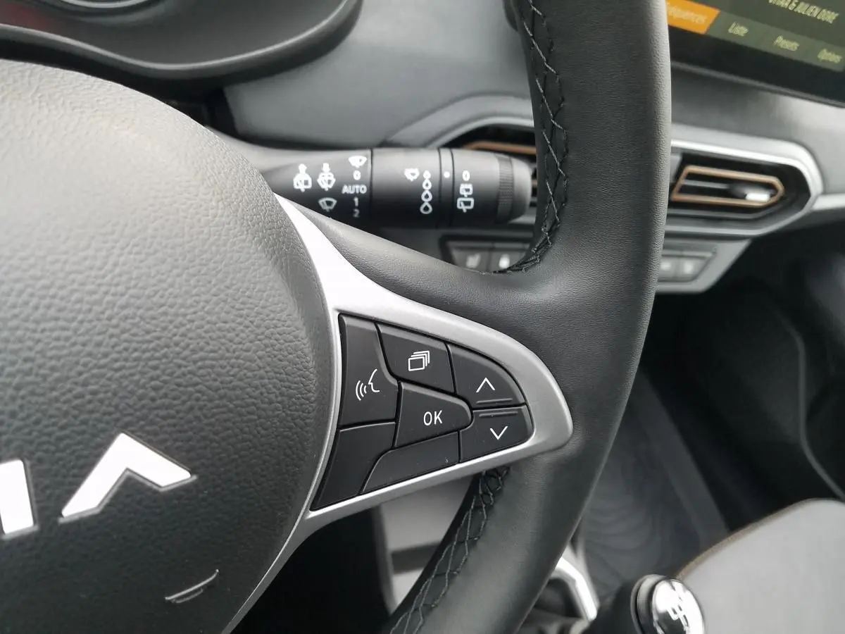 Gros plan sur le volant noir du Dacia Jogger 2025 avec commandes intégrées et partie de la console centrale visible.