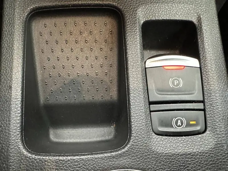 Gros plan sur la console centrale noire du Renault Captur 2025 avec commandes de frein à main électrique et arrêt auto. moteur.