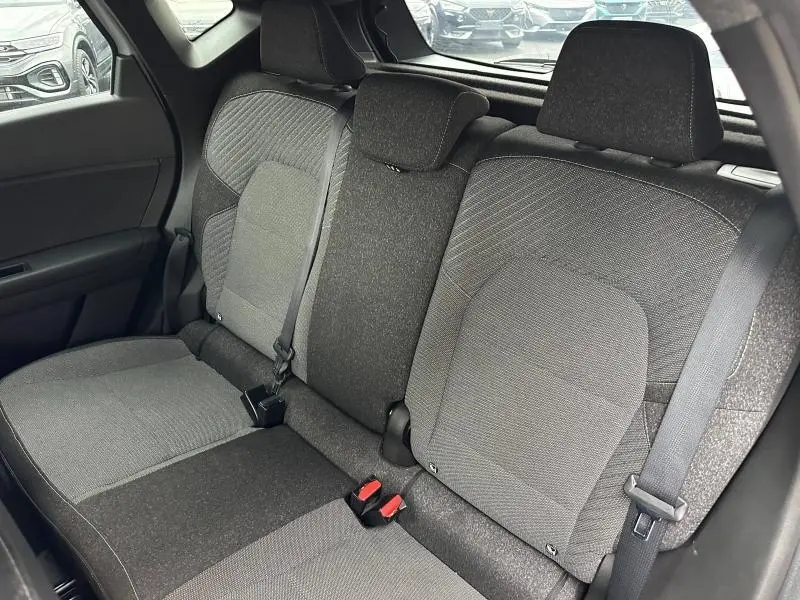 Vue intérieure arrière du Renault Captur 2025, banquette 3 places en tissu gris avec ceintures de sécurité visibles.