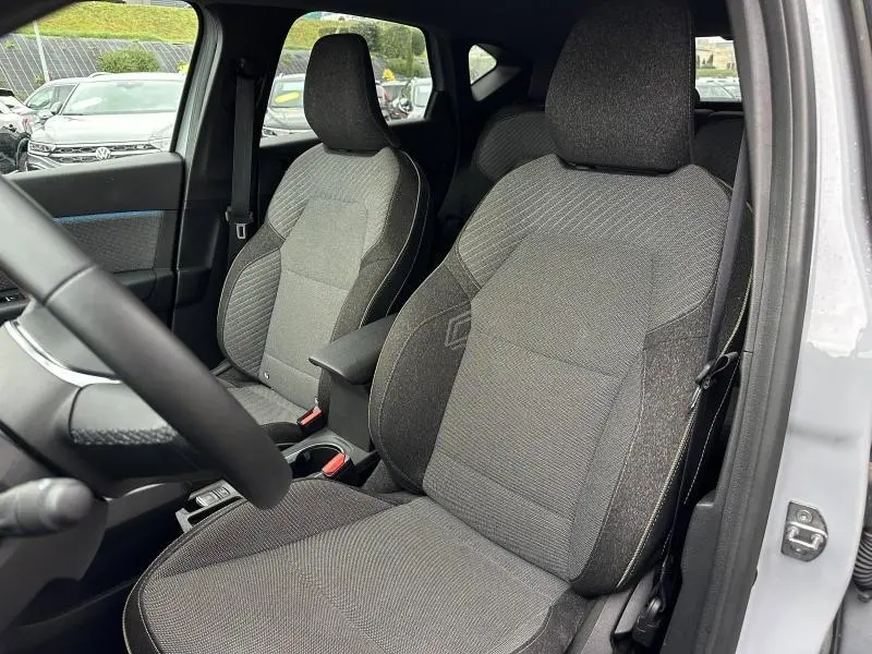 Vue intérieure côté conducteur du Renault Captur 1.0 Eco-G 2025 avec sièges gris et accoudoir central noir.