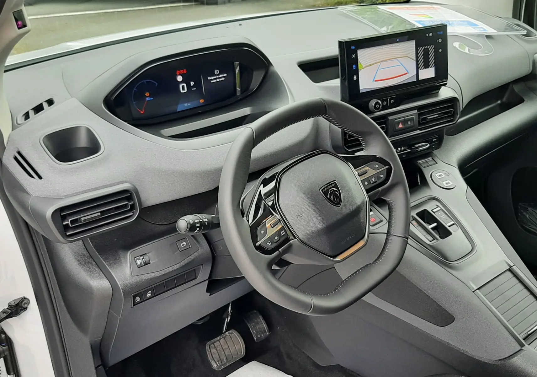 Vue intérieure côté conducteur du Peugeot Rifter 2026 blanc Kaolin, avec tableau de bord numérique et écran tactile central.