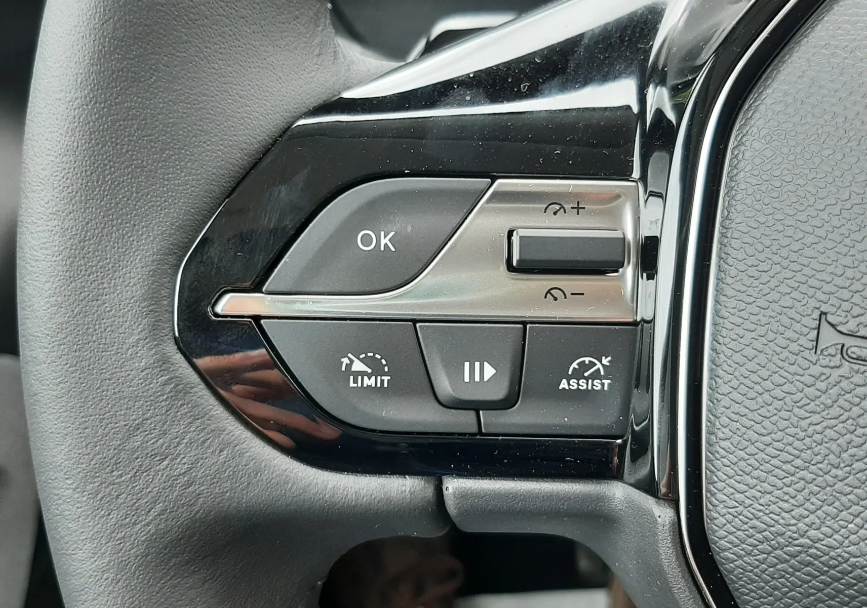Gros plan sur les commandes gauche du volant noir du Peugeot Rifter blanc Kaolin, boutons de régulateur et assistant de conduite.