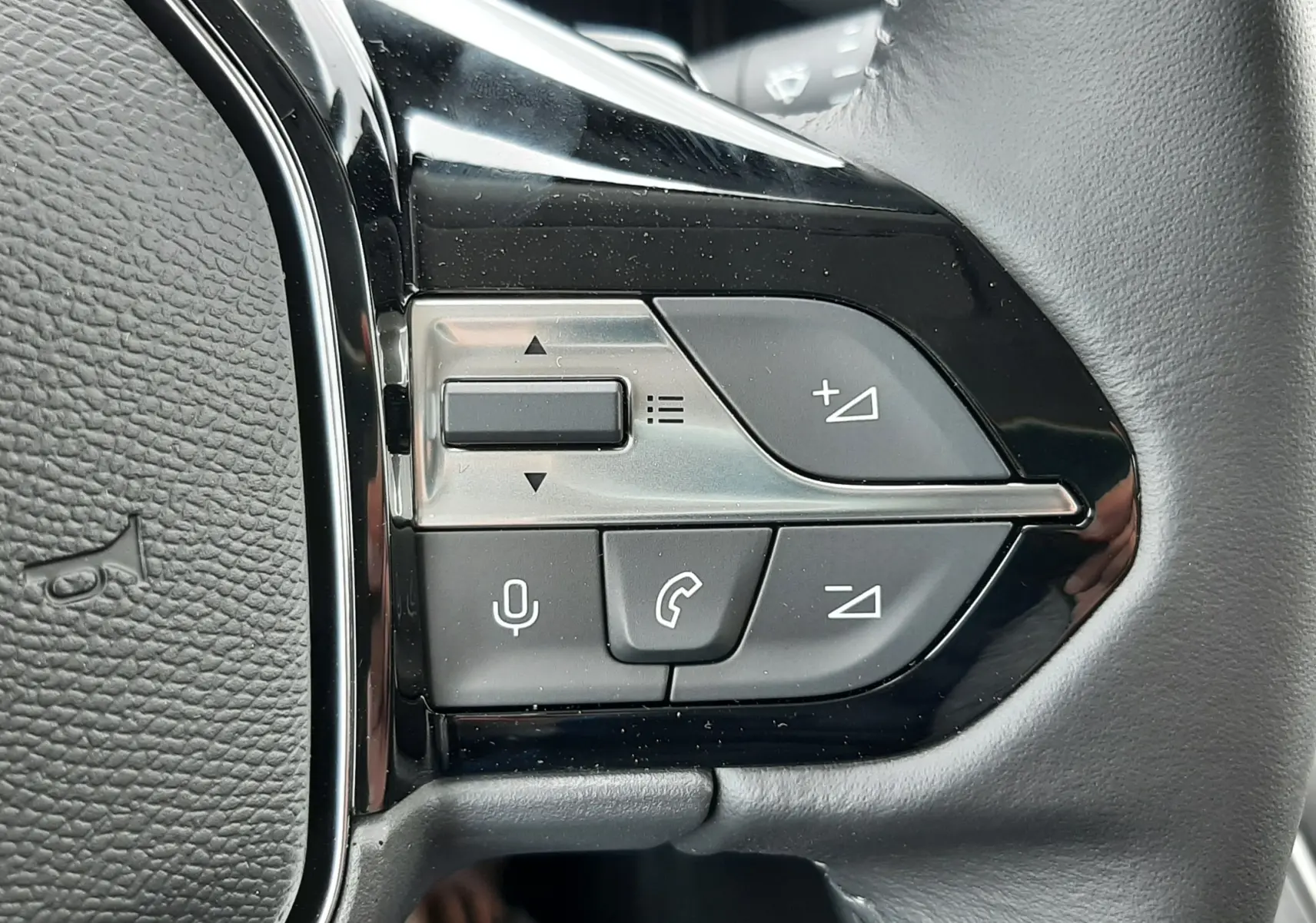 Gros plan sur les commandes multifonctions à droite du volant en cuir noir du Peugeot Rifter blanc Kaolin 2026.