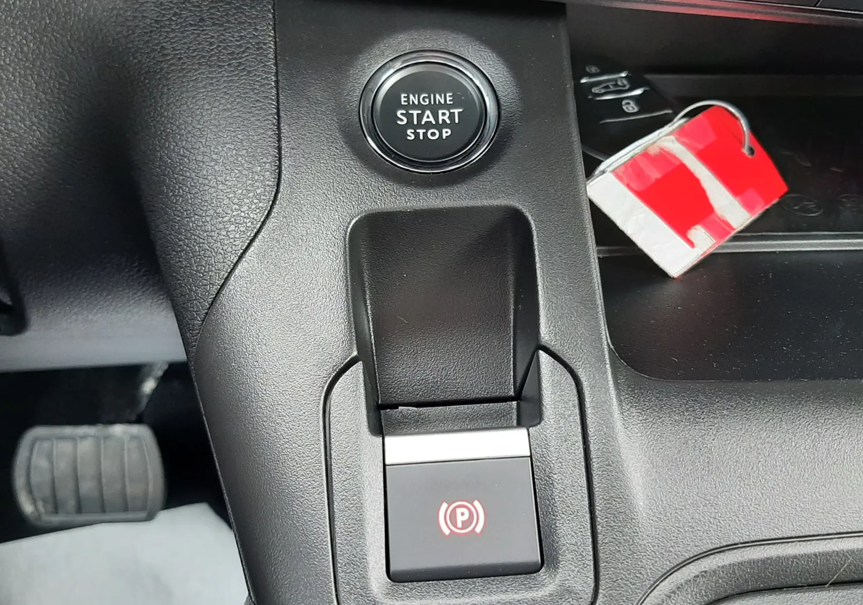 Gros plan sur le bouton start/stop moteur et la commande de frein à main électrique dans l'habitacle du Peugeot Rifter blanc Kaolin.