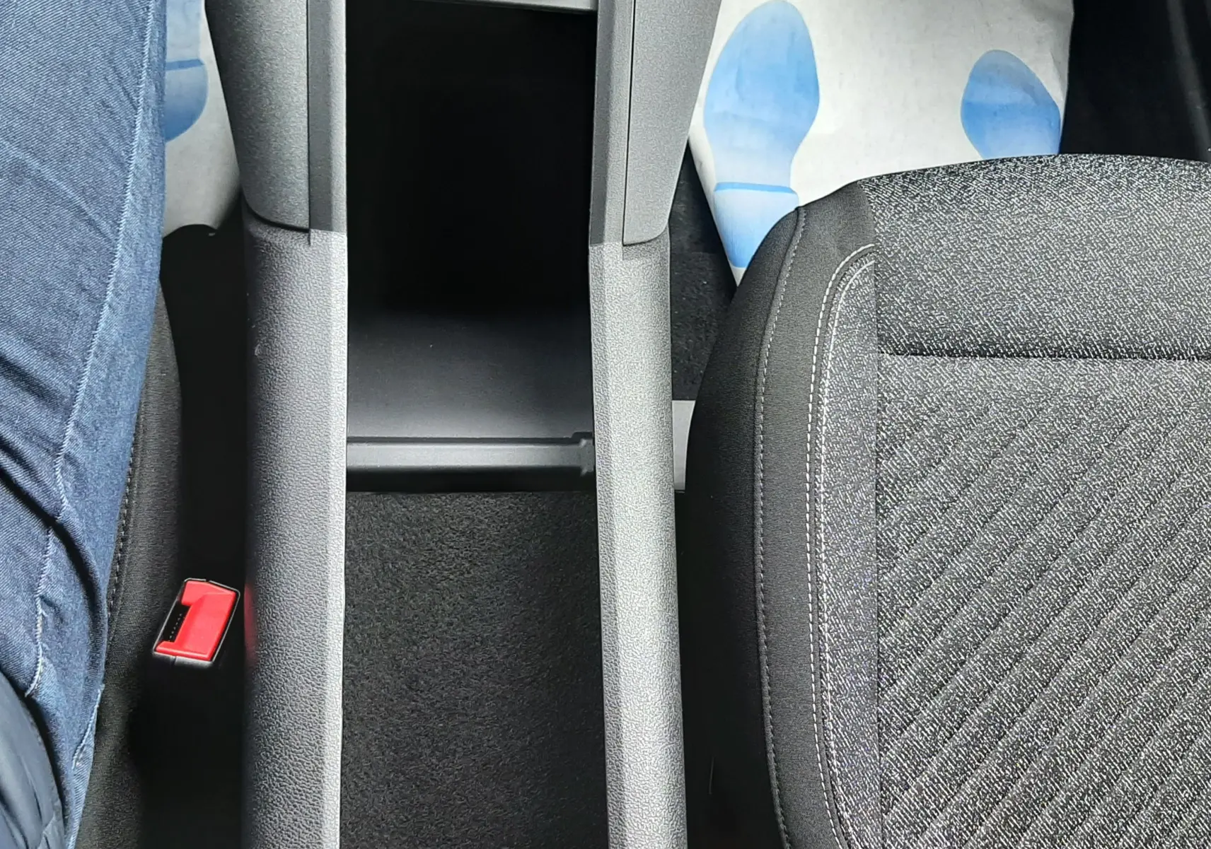 Vue plongeante sur la console centrale noire et les sièges tissu gris foncé à motifs du Peugeot Rifter blanc Kaolin.