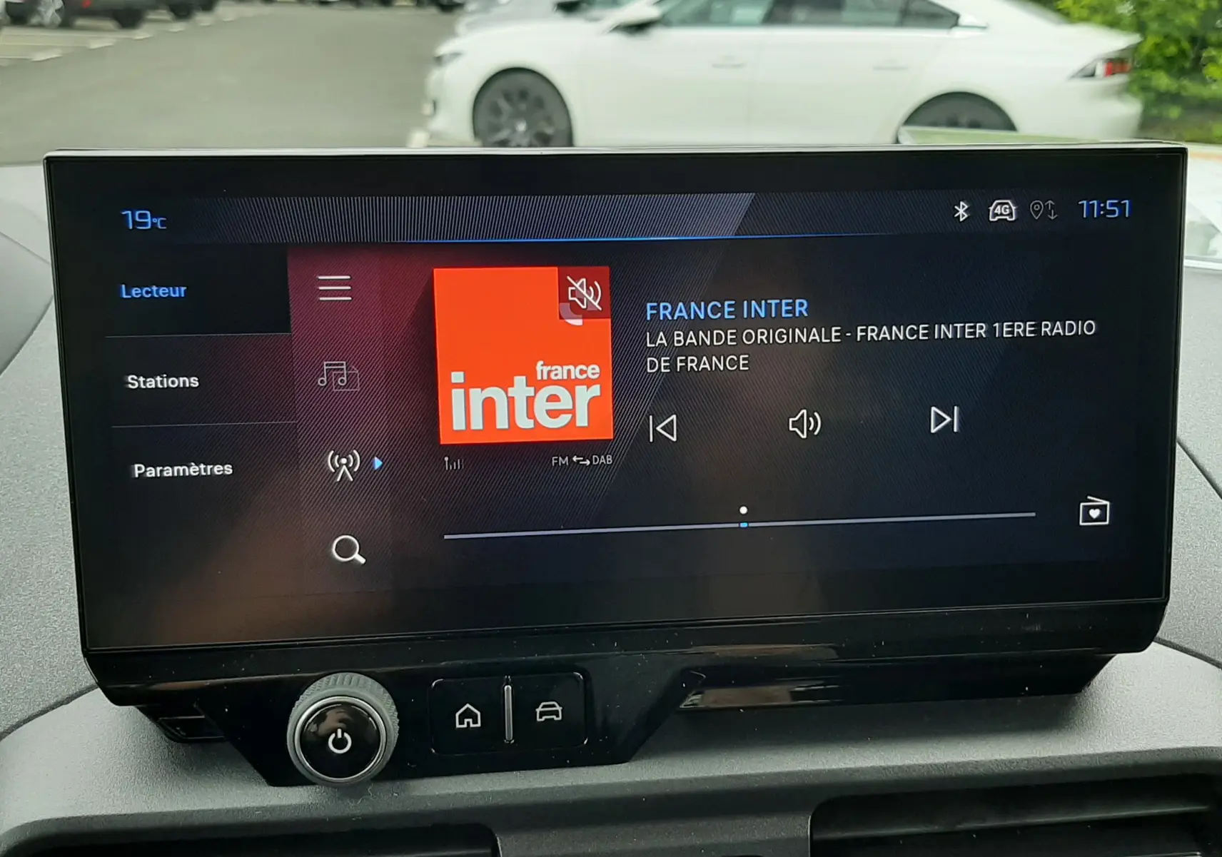 Vue avant intérieure du tableau de bord du Peugeot Rifter blanc Kaolin, avec écran tactile affichant la radio France Inter.