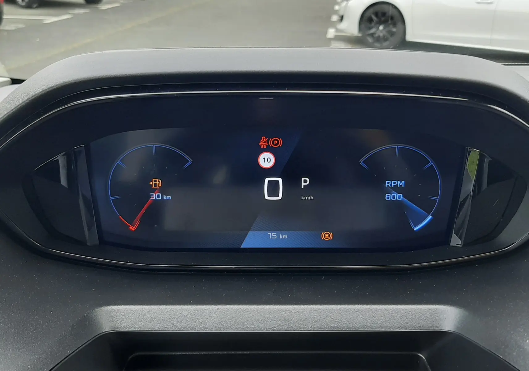 Tableau de bord numérique du Peugeot Rifter blanc, affichant vitesse à 0 km/h et jauge de carburant presque vide.