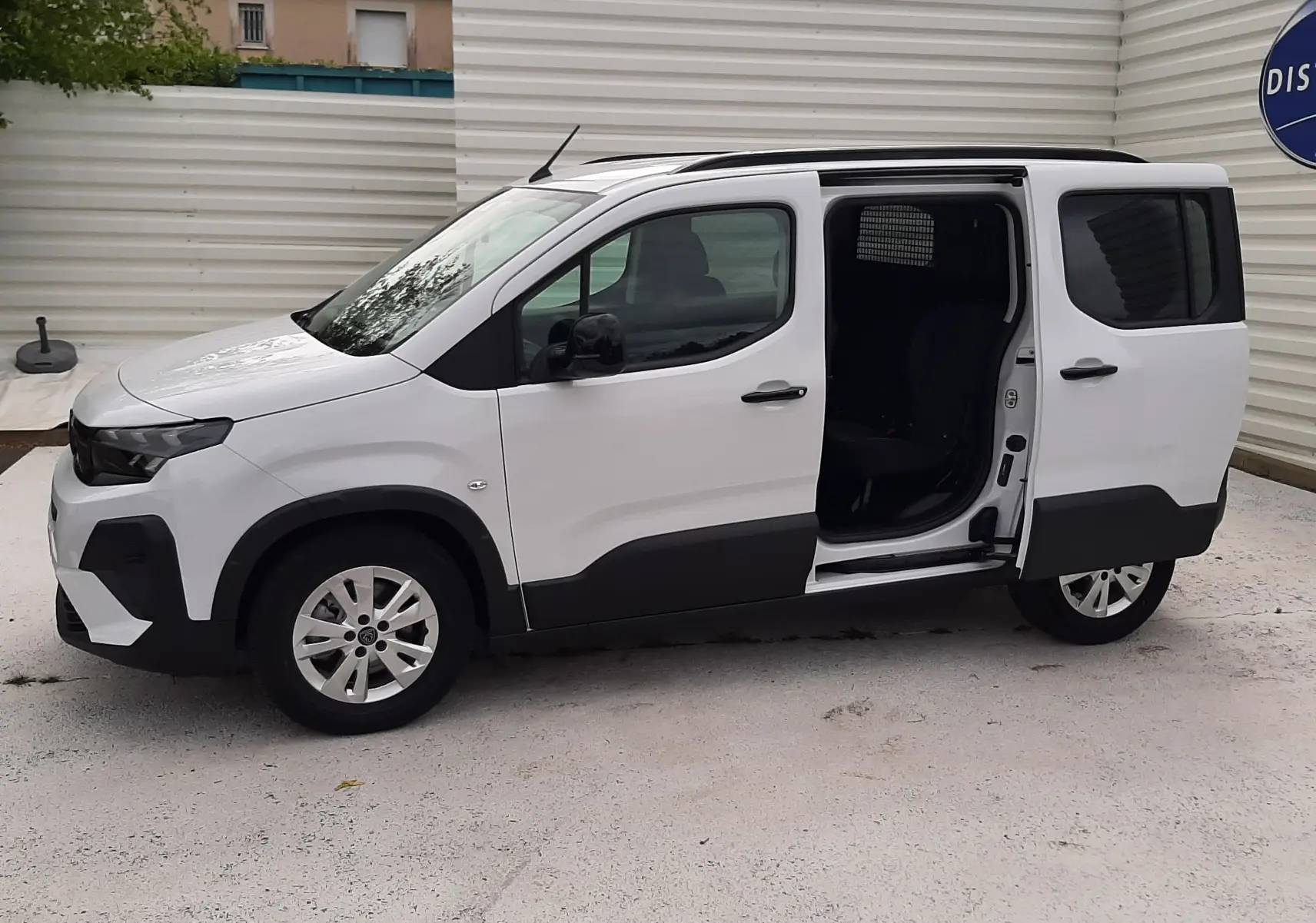 Peugeot Rifter blanc Kaolin vu de profil droit avec porte coulissante ouverte, montrant l'intérieur noir.