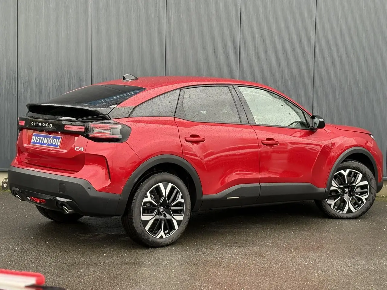 Vue 3/4 arrière droite d'une Citroën C4 rouge Elixir avec jantes alliage et toit noir contrasté.