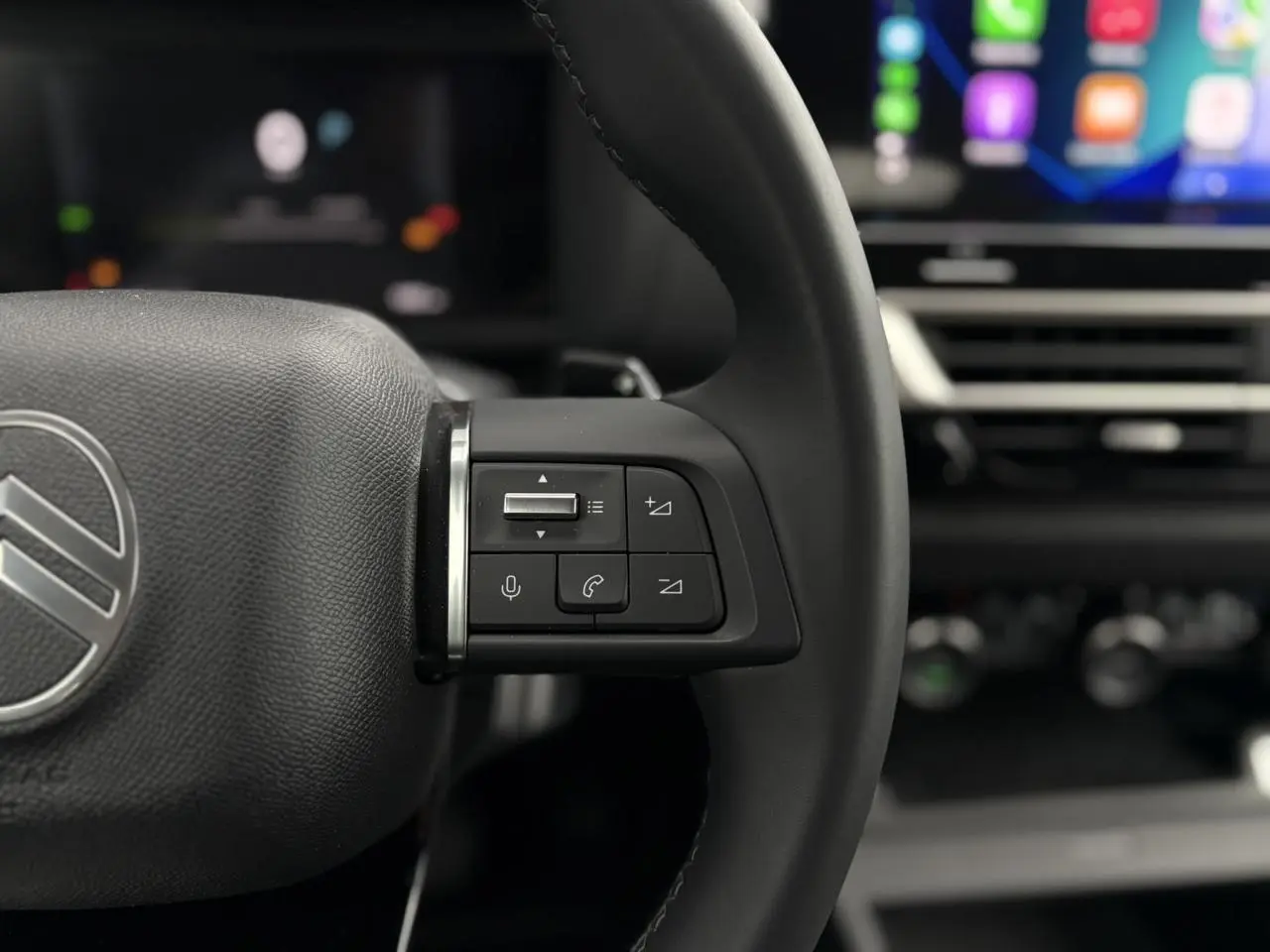 Gros plan sur les commandes vocales et audio au volant cuir de la Citroën C4 Hybrid 2025, intérieur noir.