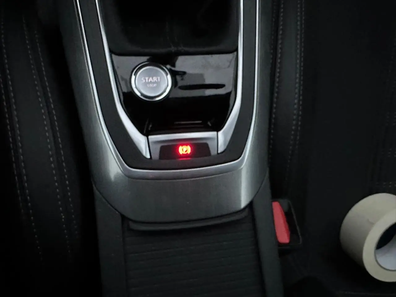 Gros plan sur la console centrale de la Peugeot 308 gris Artense, montrant le bouton start et le frein de parking électrique allumé.