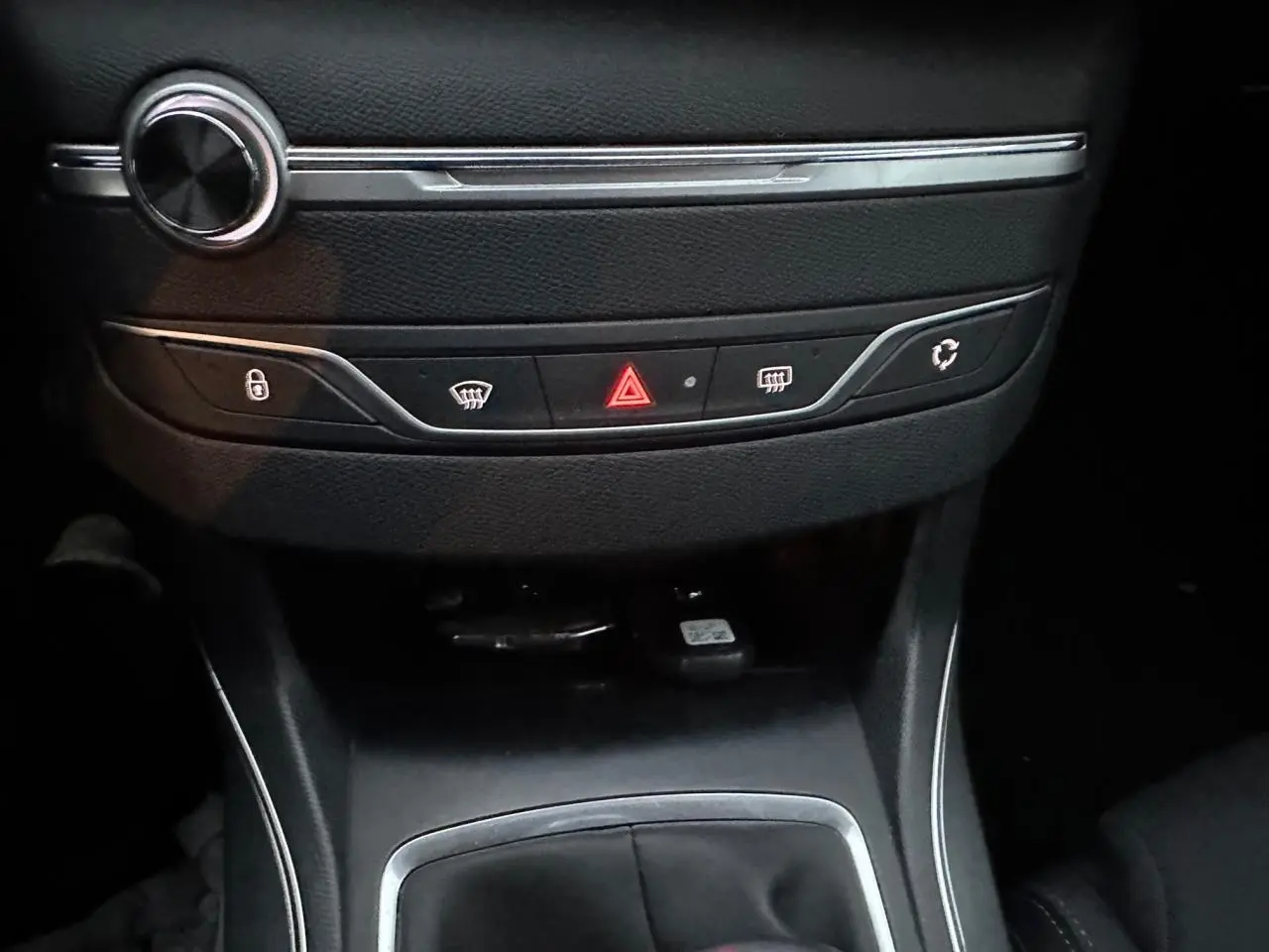 Détail de la console centrale noire de la Peugeot 308 avec les boutons de verrouillage, dégivrage et alerte au centre.