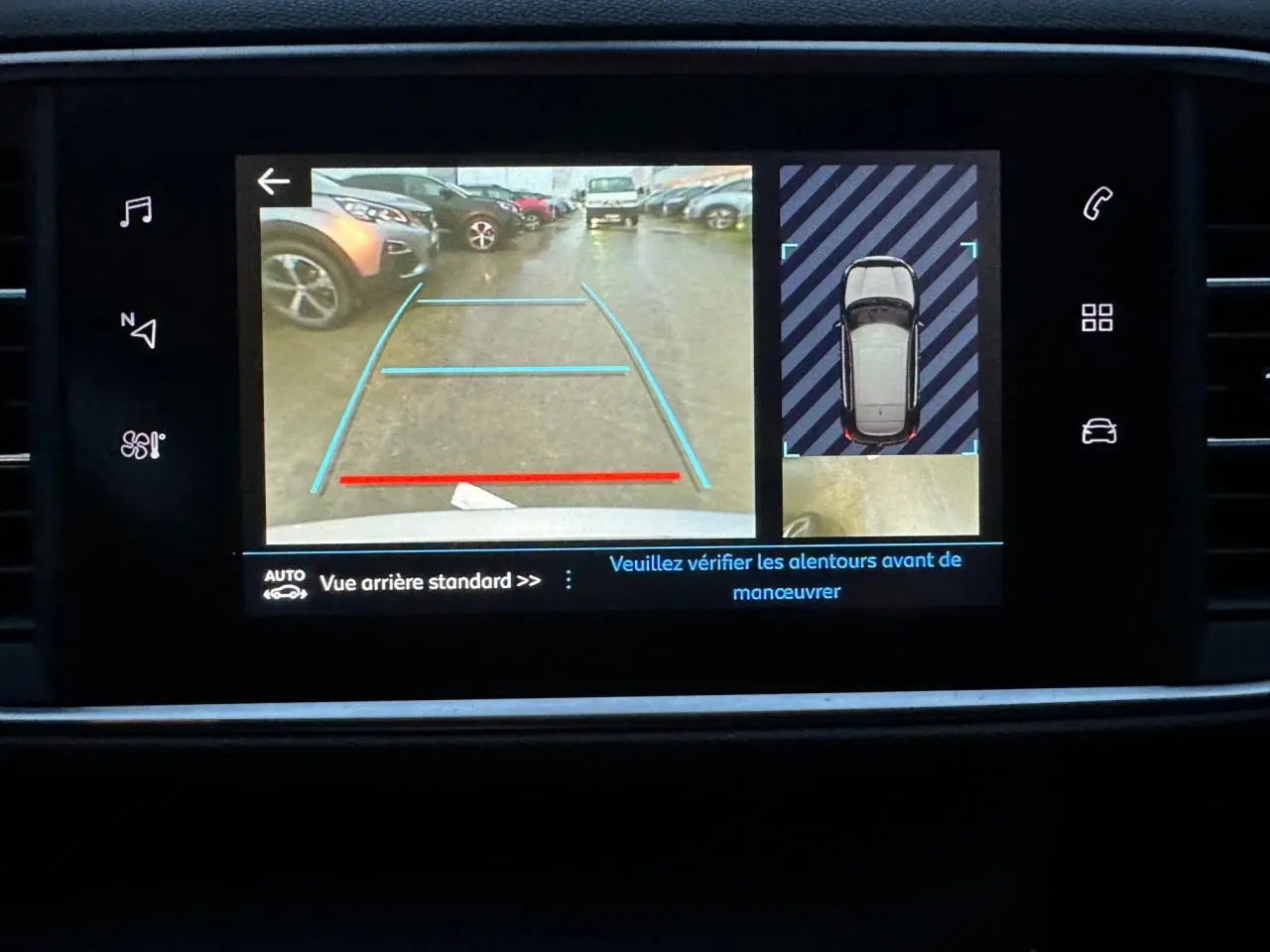 Écran tactile de la Peugeot 308 gris Artense montrant la caméra de recul avec aides visuelles au stationnement.