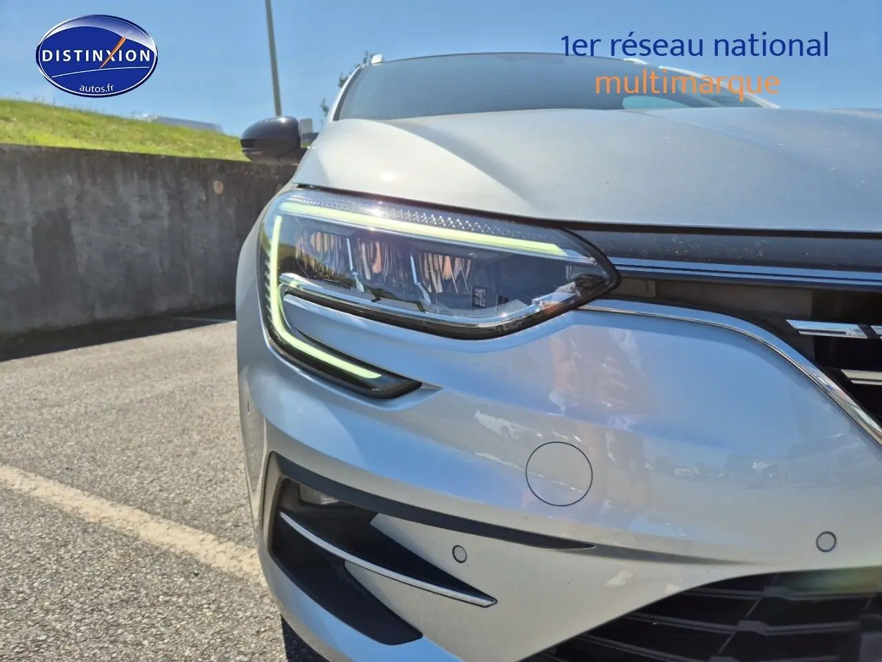 Gros plan sur le phare avant gauche d’une Renault Mégane Break gris Titanium avec détails LED et calandre chromée.