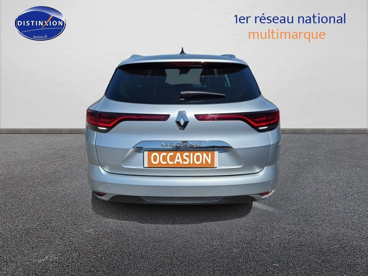Vue arrière d'une Renault Mégane Break gris titanium 2024 avec feux LED et barres de toit visibles.