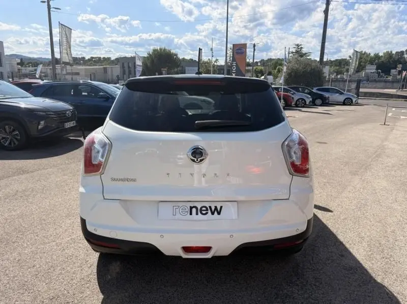 Vue arrière d'un SsangYong Tivoli blanc 2017 avec toit noir et logo visible sur un parking extérieur.