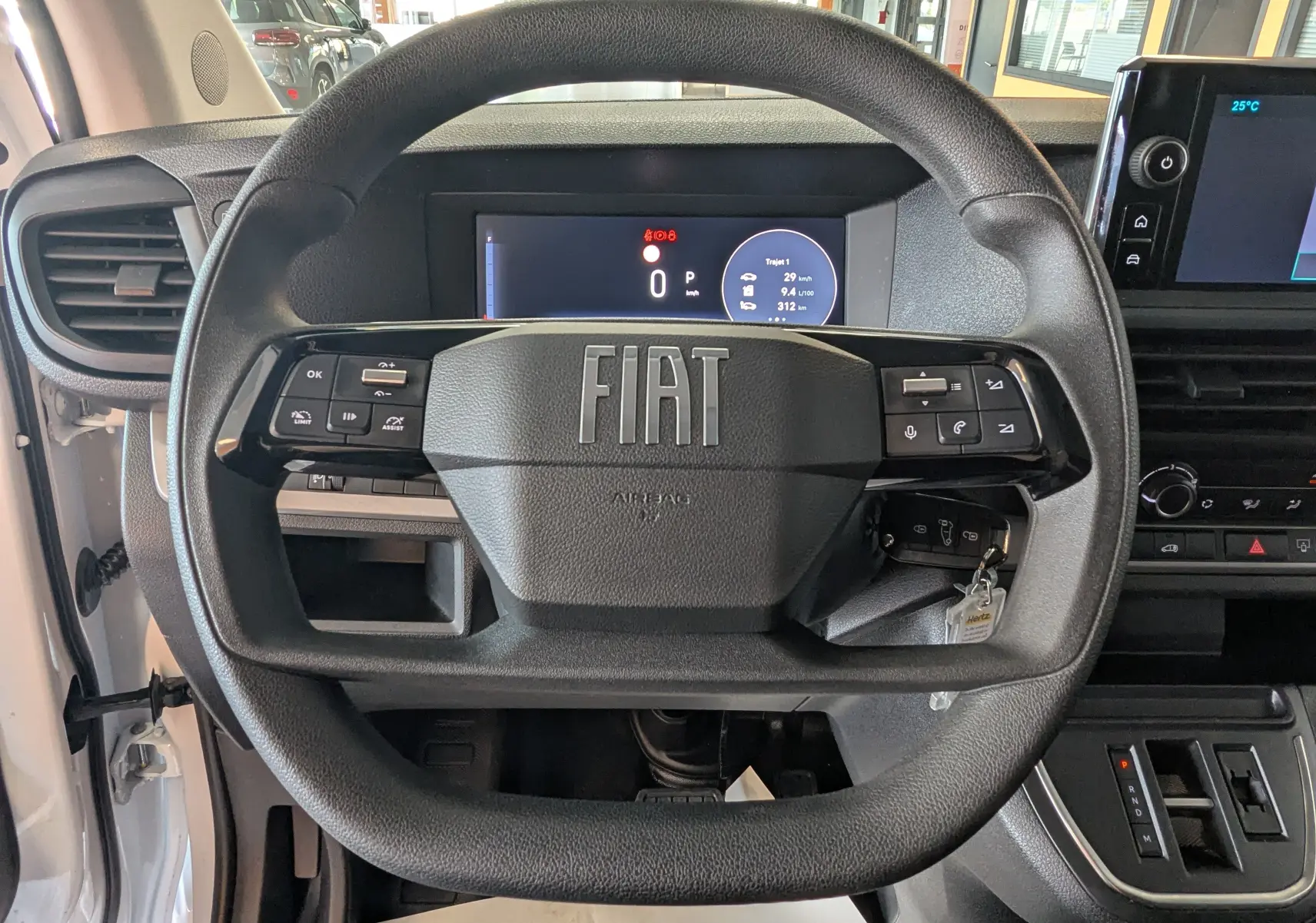 Vue rapprochée du volant noir du Fiat Scudo Fourgon XL 145 EAT8 2024 avec tableau de bord digital et commandes intégrées.