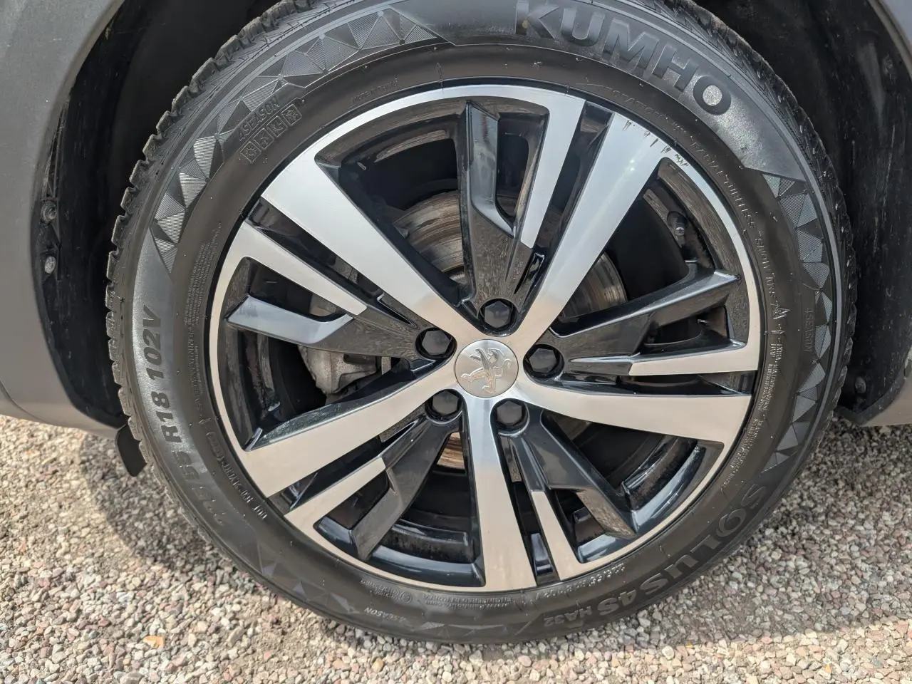 Gros plan sur la jante alliage 18 pouces bi-ton noir et argent du Peugeot 5008 gris 2023 version GT.