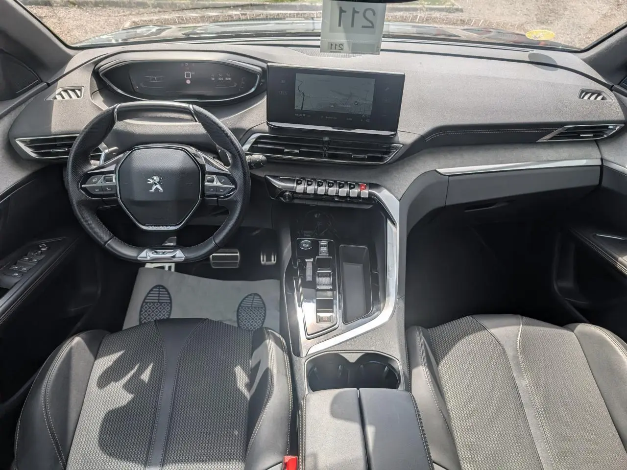 Vue intérieure avant du Peugeot 5008 GT 2023, tableau de bord noir avec écran tactile et volant compact cuir.