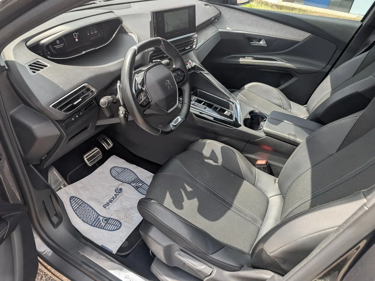 Vue intérieure côté conducteur du Peugeot 5008 gris 2023, mettant en valeur le volant compact GT et la console centrale moderne.