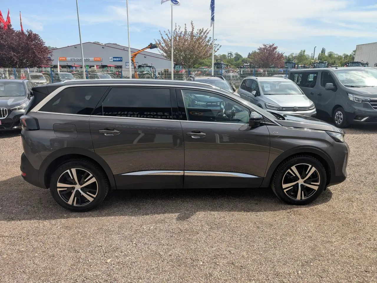 Profil droit d’un Peugeot 5008 gris métallisé 2023 GT avec jantes alliage bi-ton et vitres arrière surteintées.