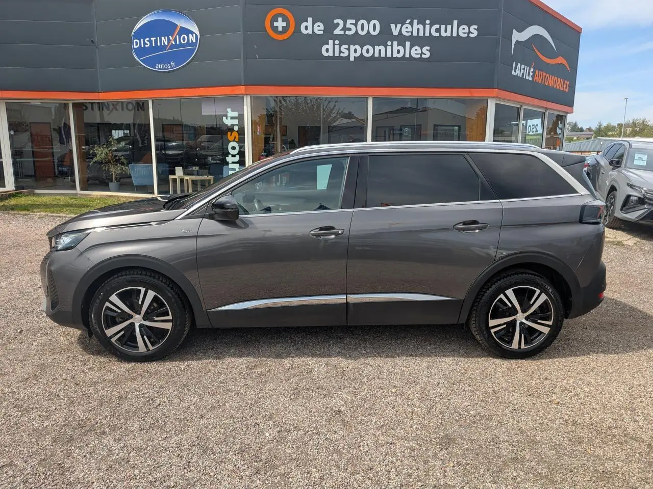 Peugeot 5008 gris métallisé vue de profil côté gauche, avec jantes bi-ton et vitres arrière surteintées.