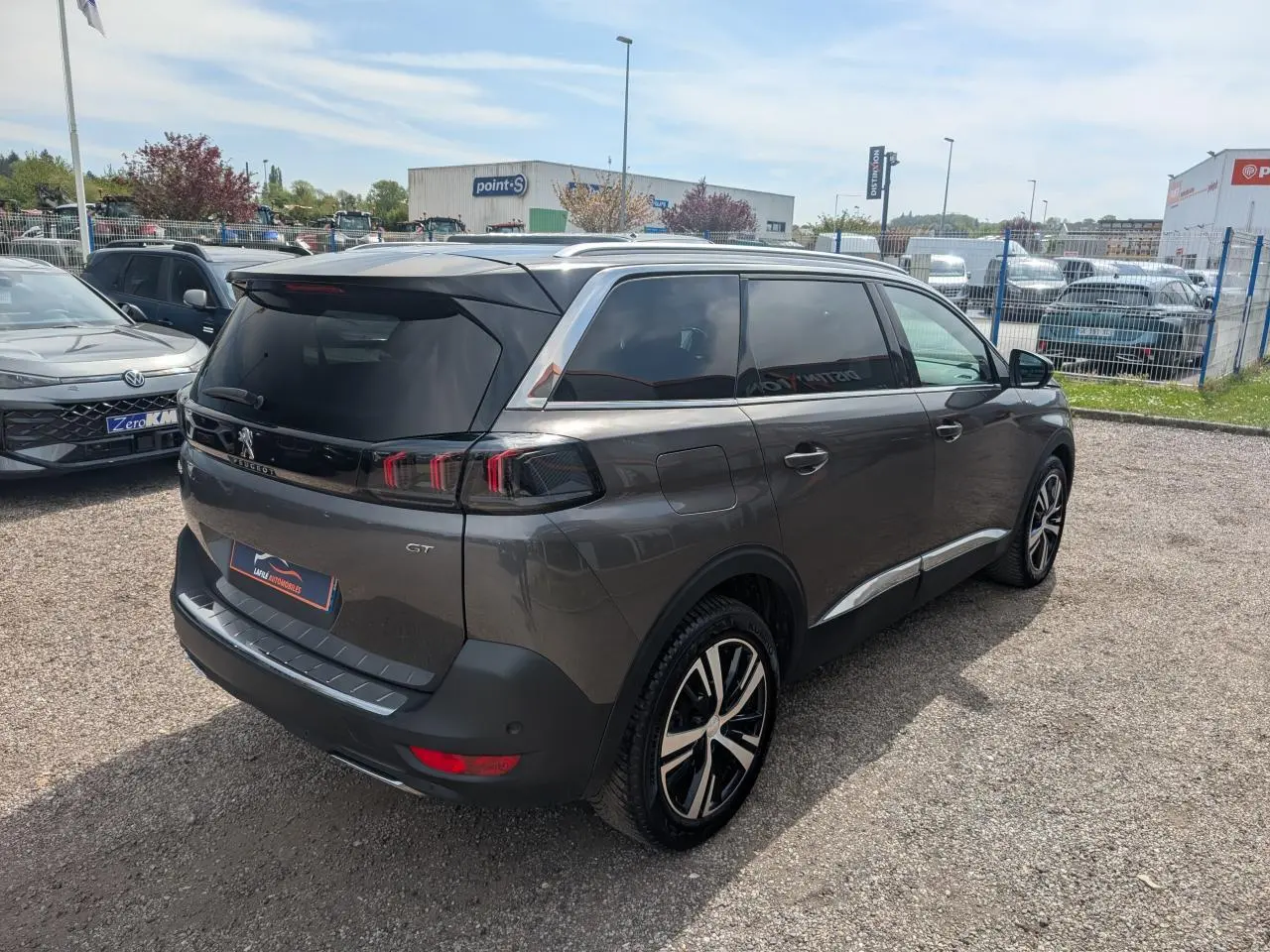 Peugeot 5008 GT gris métallisé vue 3/4 arrière droit, feux arrière LED 3D et jantes alliage bi-ton visibles.