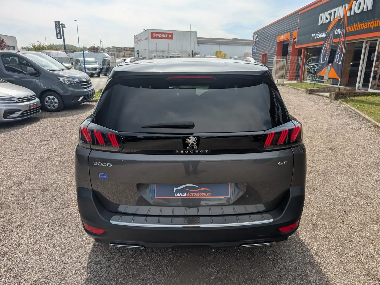 Vue arrière d'un Peugeot 5008 gris métallisé 2023 GT avec feux LED 3D et hayon mains libres sur parking.