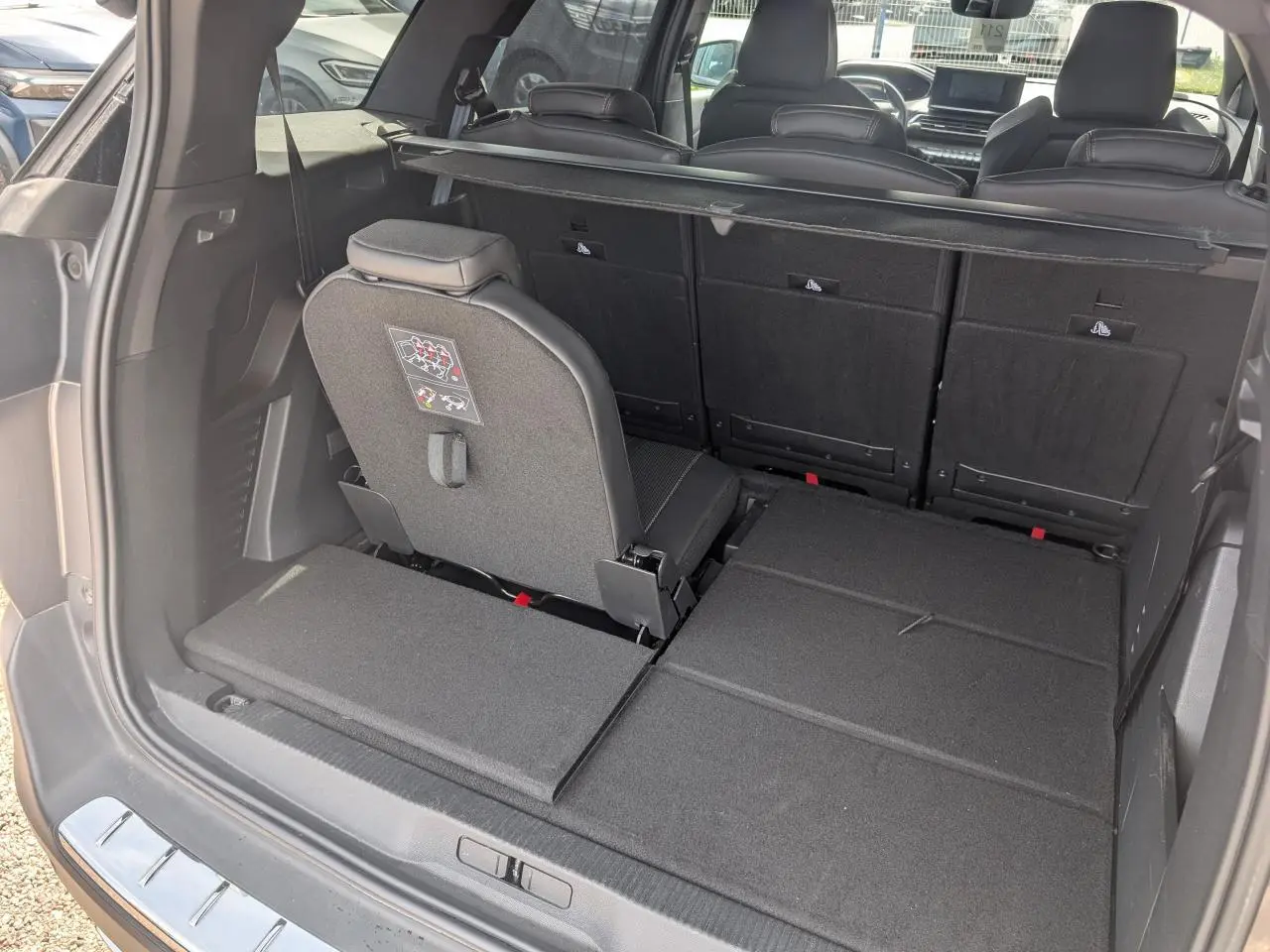 Vue arrière du coffre du Peugeot 5008 gris 2023 avec siège arrière droit relevé et banquette rabattue.