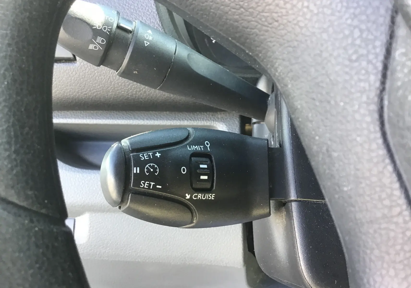 Gros plan sur le commodo de régulateur et limiteur de vitesse noir dans l'habitacle du Citroën Jumpy blanc 2021.