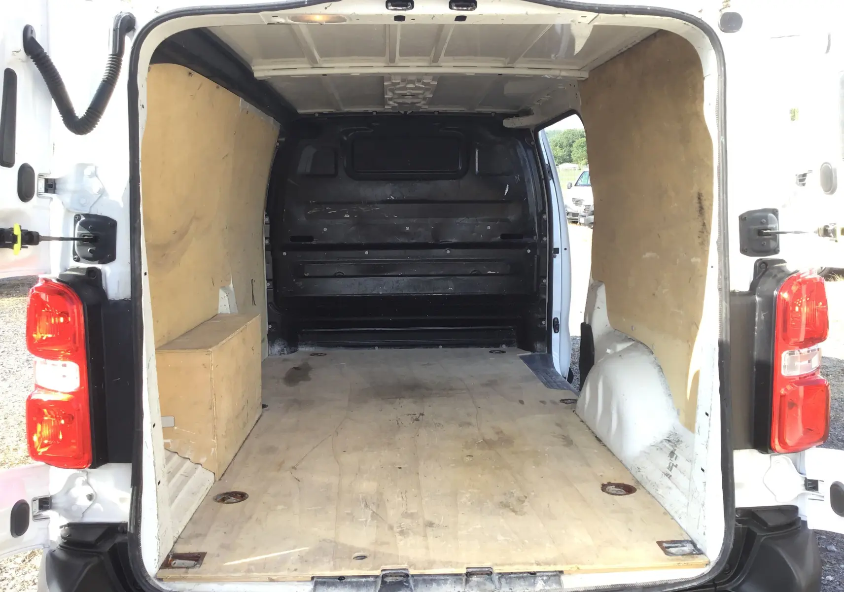 Vue arrière ouverte du Citroën Jumpy XL blanc de 2021, montrant l'espace de chargement en bois et les parois latérales protégées.