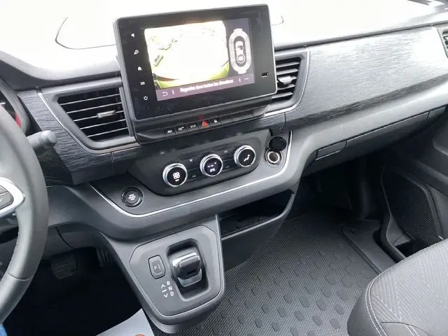 Intérieur du Renault Trafic Noir 2025, vue sur tableau de bord avec écran tactile, commandes clim et levier de boîte auto.