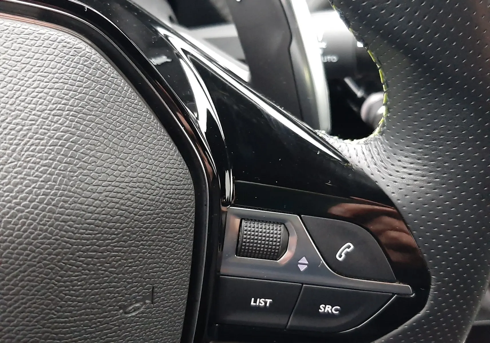 Gros plan sur la commande droite du volant perforé noir du Peugeot 2008 2023 blanc nacré avec palettes au volant.